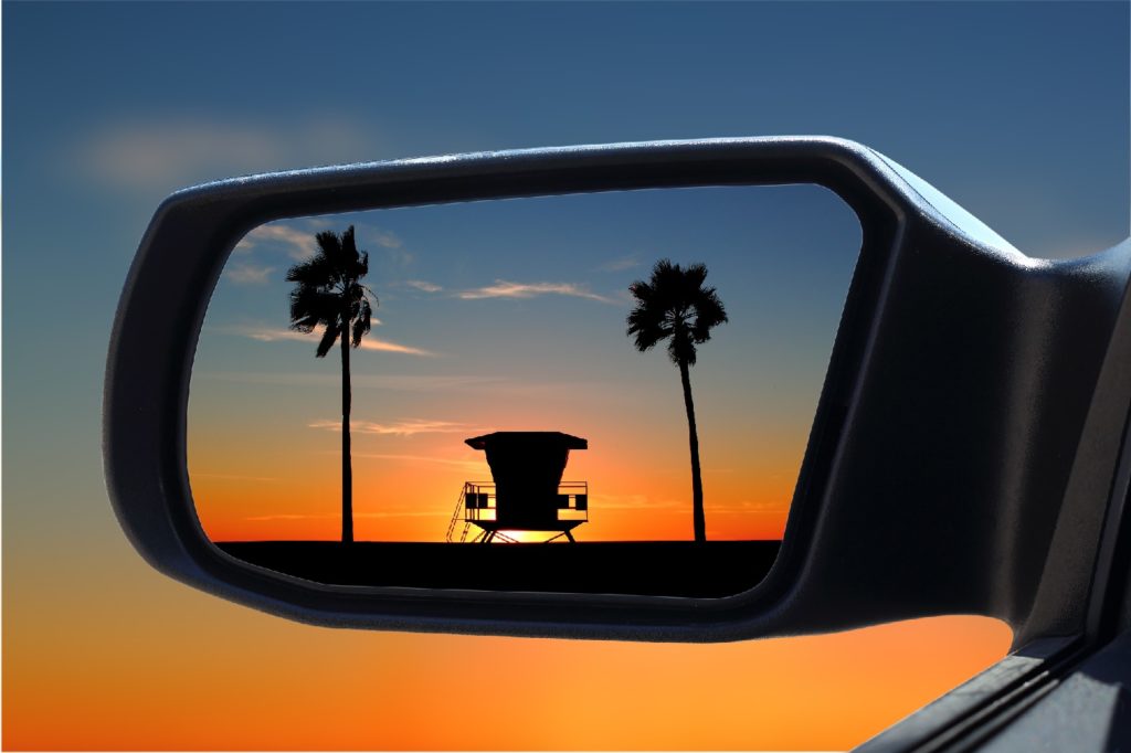 Beach in rear-view mirror of car
