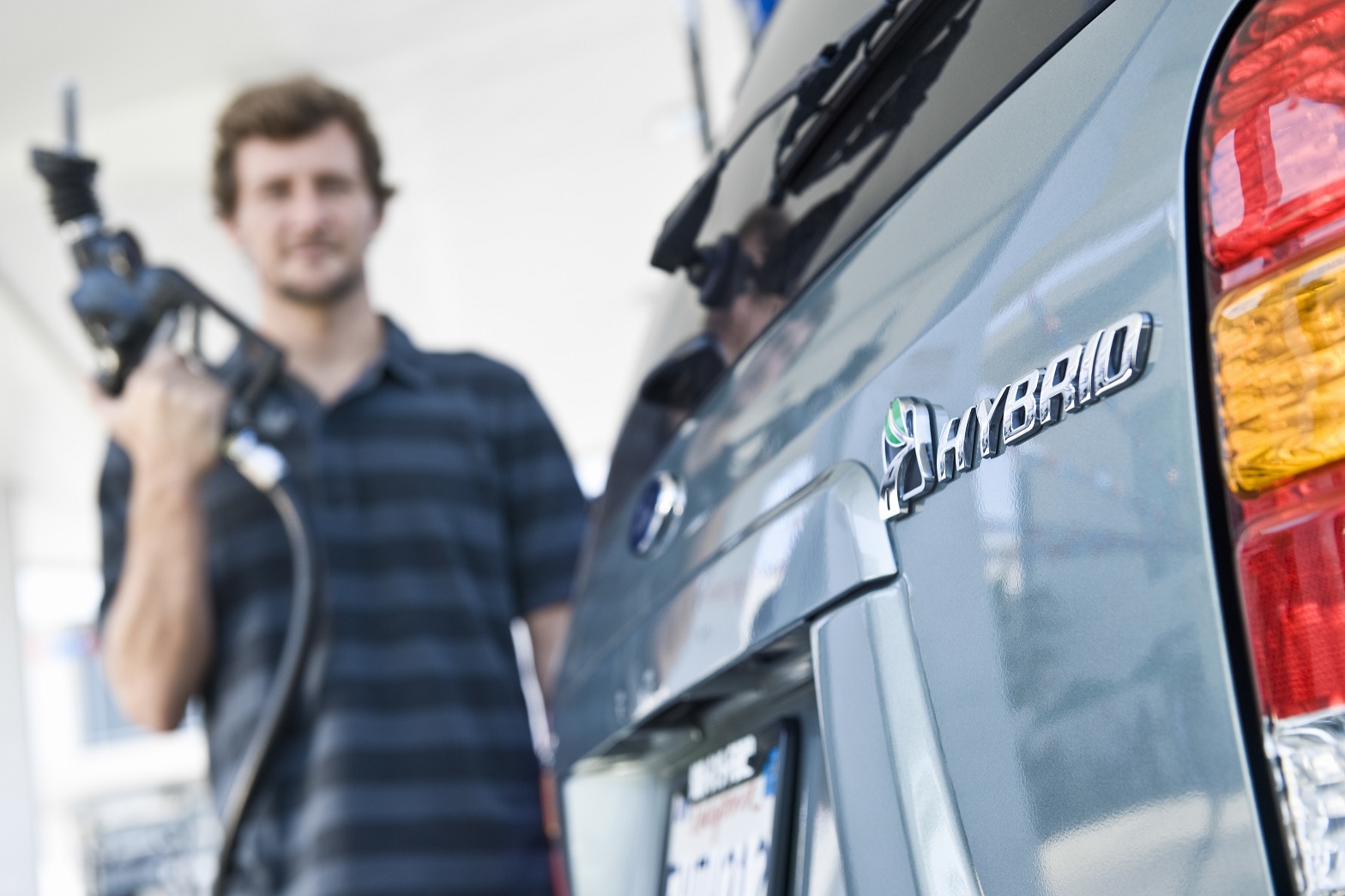View of a blurred man refueling a cropped hybrid car