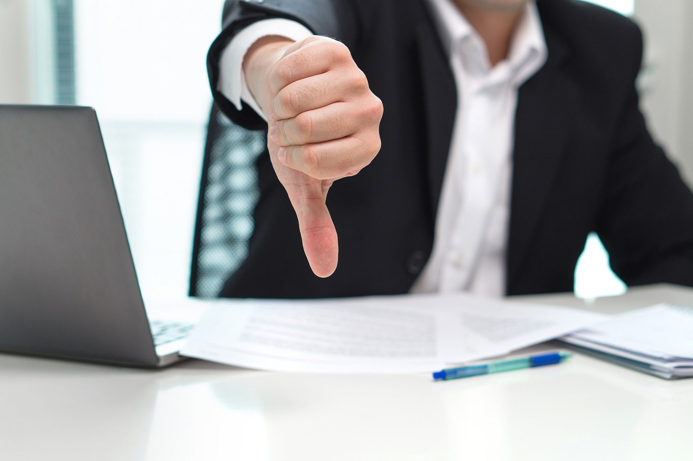 Business man showing thumbs down in office.